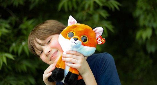 Kid smiling holding fox beanie baby