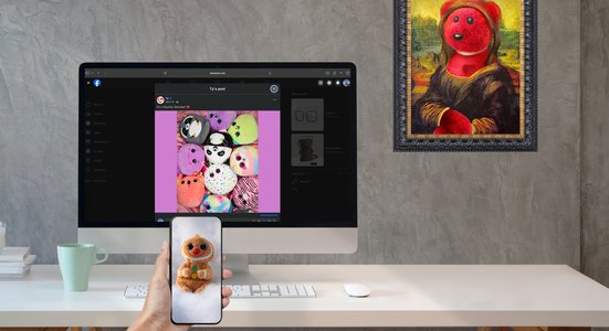 Holding phone with gingerbread beanie baby, screen behind features Squishy Beanies and on the wall is mona lisa painting with beanie baby.