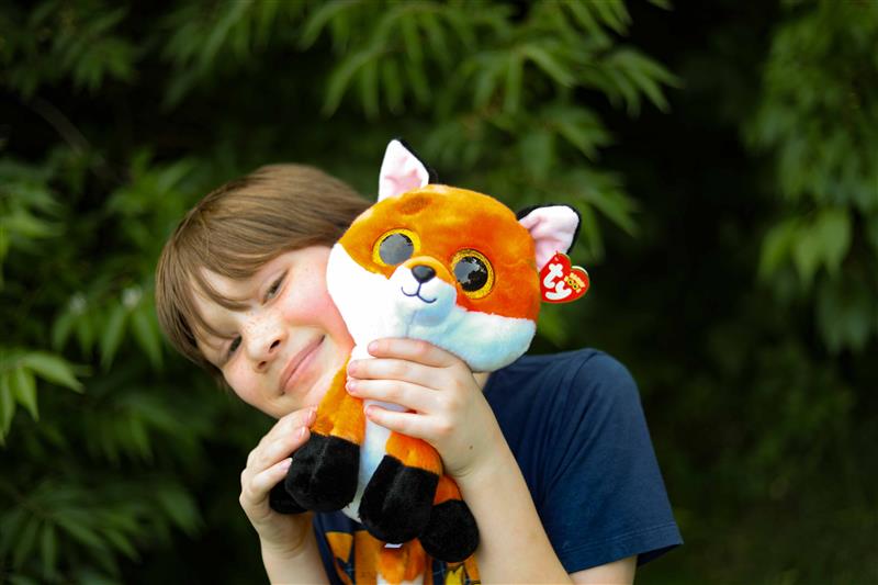 Kid smiling holding fox beanie baby